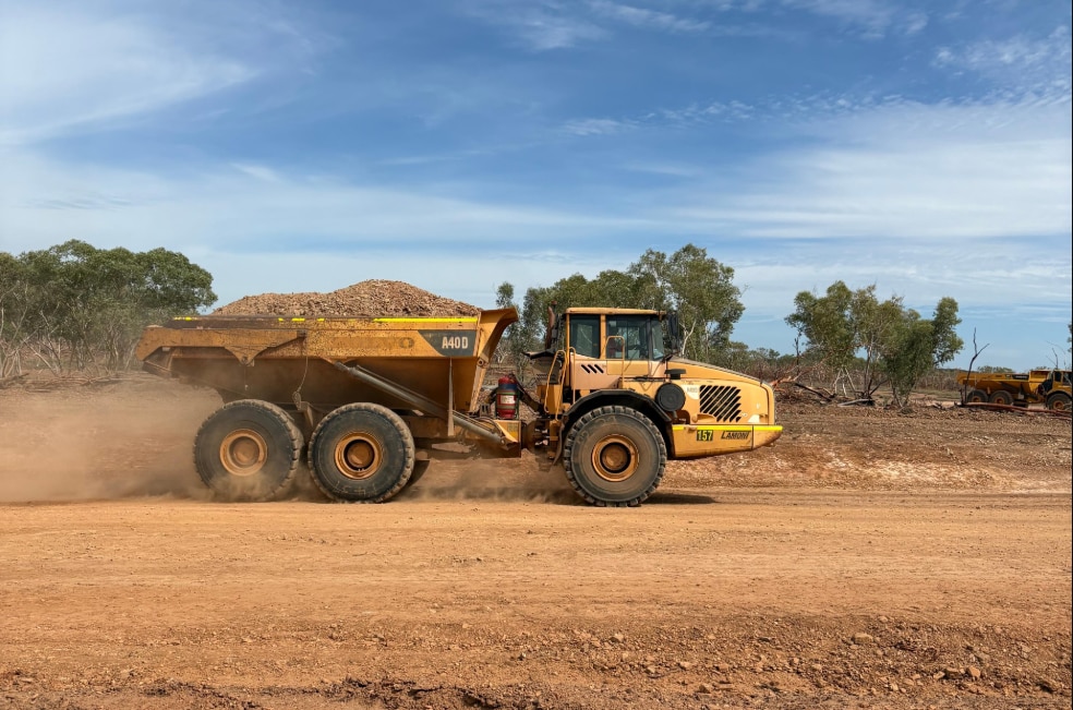 A dump truck driving over red dirt on mine site