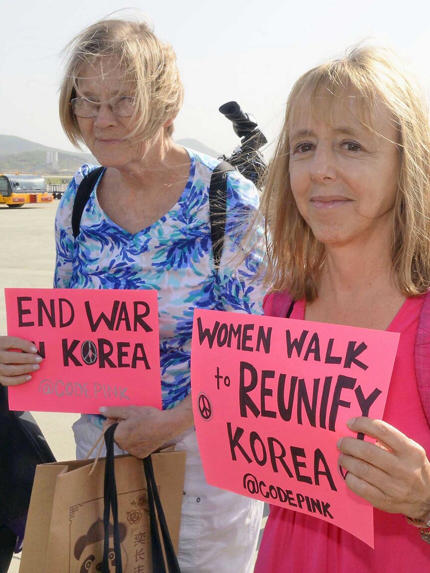 Women peace activists hold up sign at Pyongyang airport