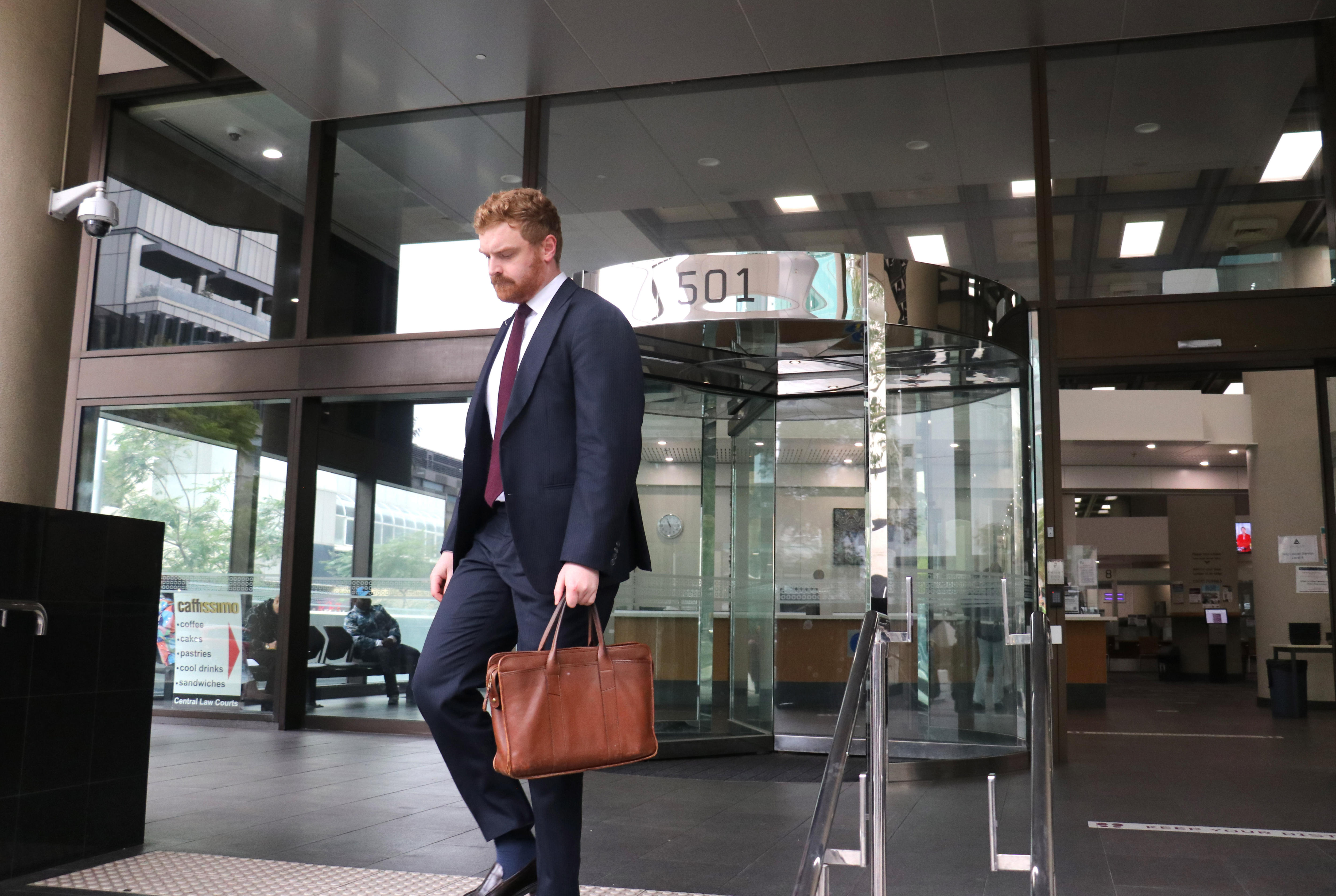 A lawyer leaves a court building holding a bag.