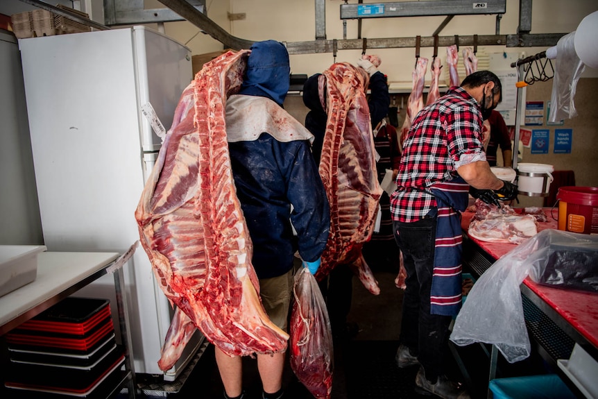 Delivery men carry meat into the cutting room at Campisi Butchery where staff prepare cuts for sale.