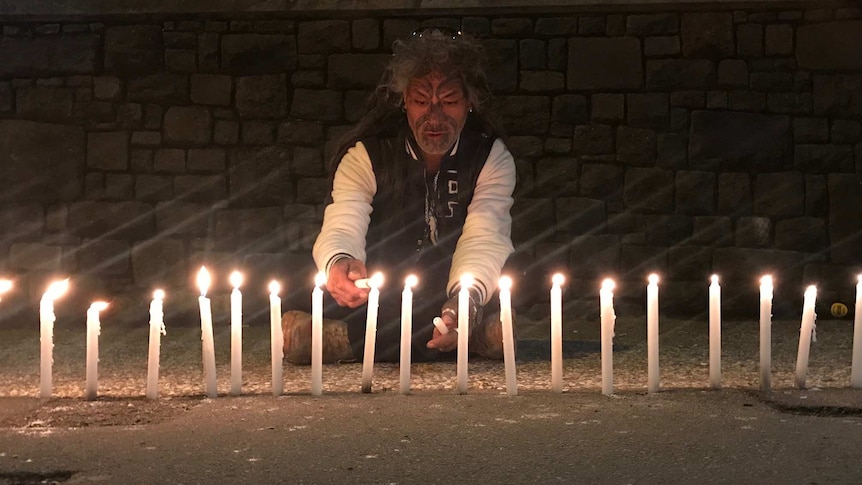 a man lights candles for victims of the Christchurch terrorist attack