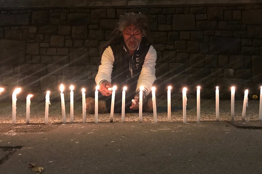 a man lights candles for victims of the Christchurch terrorist attack