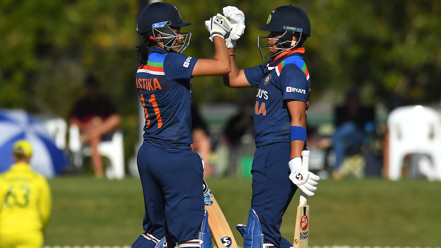 Yastika Bhatia and Shafali Verma high-fove each other while on the field, wearing their batting gear