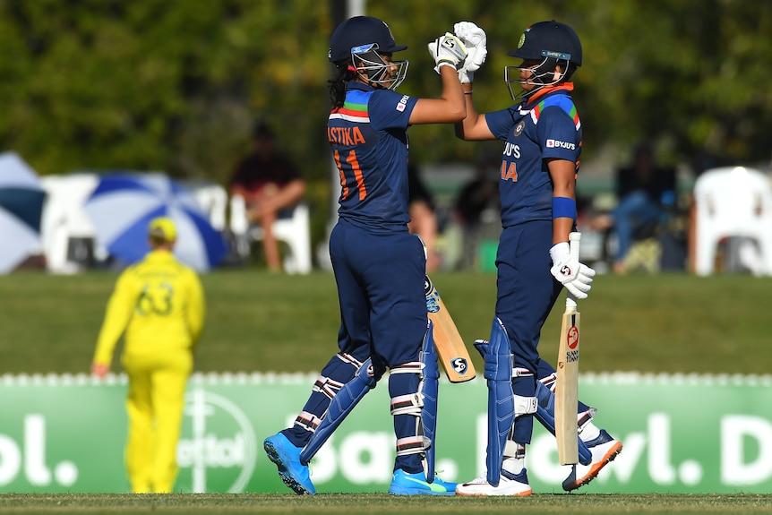 Yastika Bhatia and Shafali Verma high-fove each other while on the field, wearing their batting gear