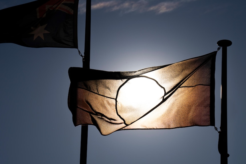 An Aboriginal flag backlit by the sun. 