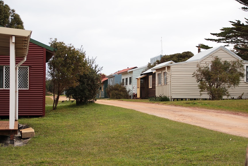 Wooden shacks lie a dirt track