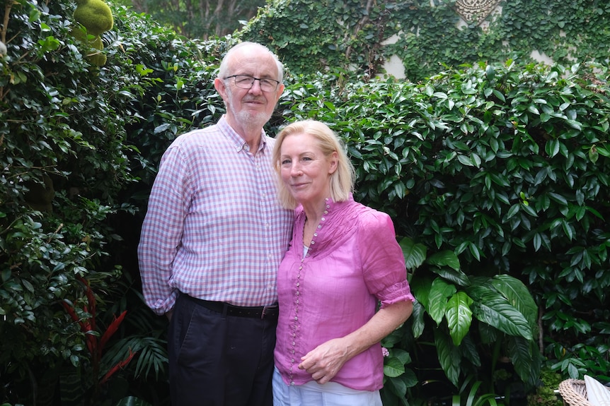 A man in checked shirt and woman in pink shirt standing in garden