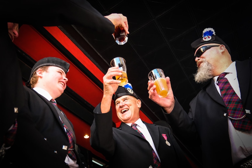 Three soldiers raise a toast after Anzac Day march in Sydney