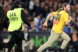 A pitch invader is chased by a security ground on a football field