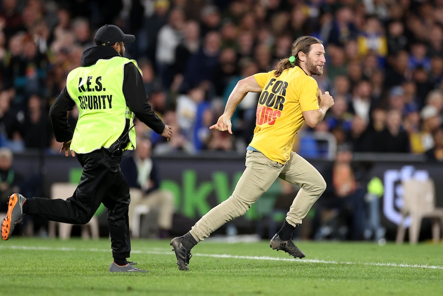 A pitch invader is chased by a security ground on a football field