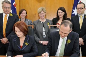 Julia Gillard and Bob Brown sign on the line (AAP: Alan Porritt)