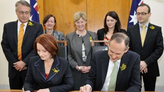 Julia Gillard and Bob Brown sign on the line (AAP: Alan Porritt)