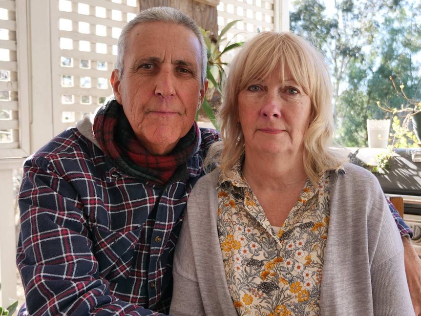 A man and a woman sitting close to each other on a verandah