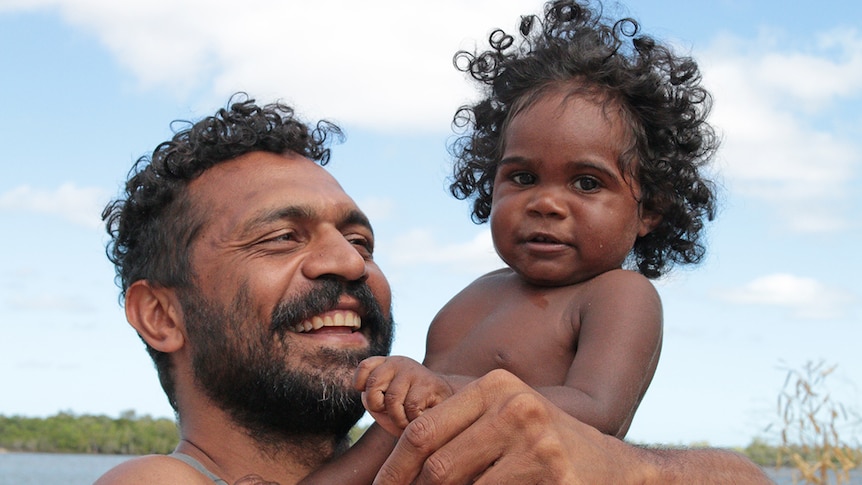 Bruce Martin holds Taizeek Watt in Aurukun in Far North Queensland.