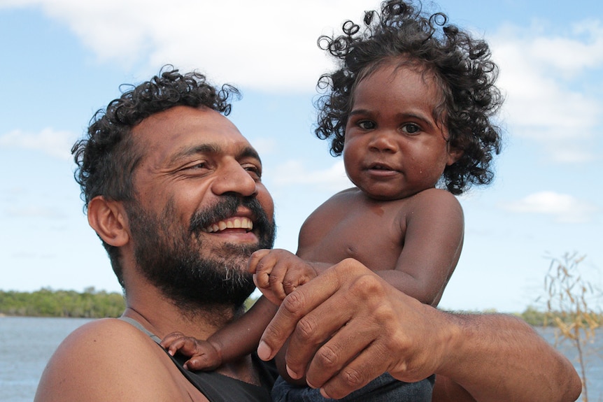 Bruce Martin holds Taizeek Watt in Aurukun in Far North Queensland.