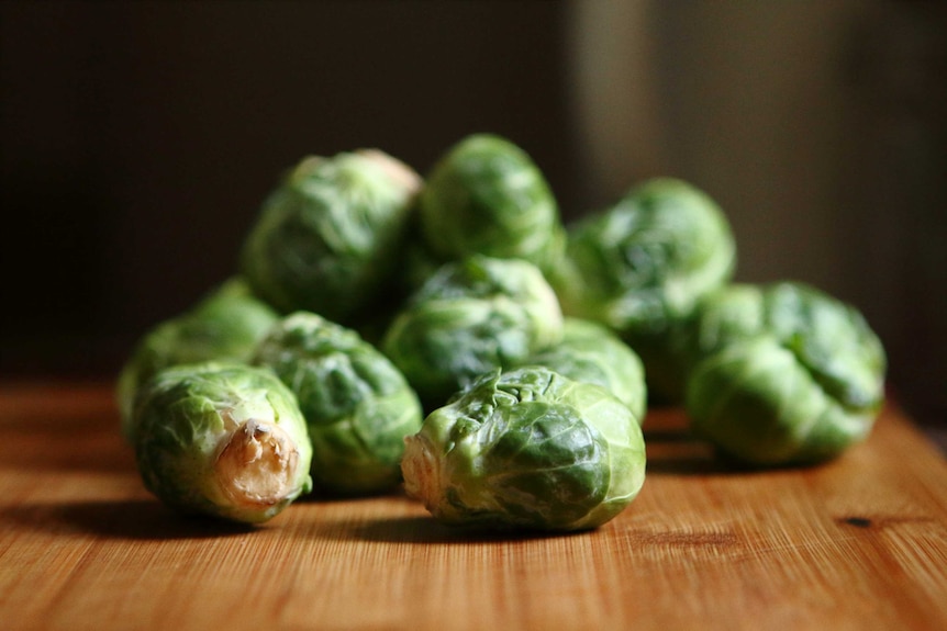 Brussel sprouts rest on a chopping board