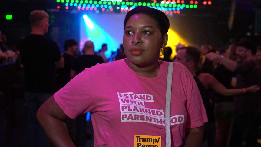 A woman looking proud while wearing a t-shirt which reads "I stand with Planned Parenthood"