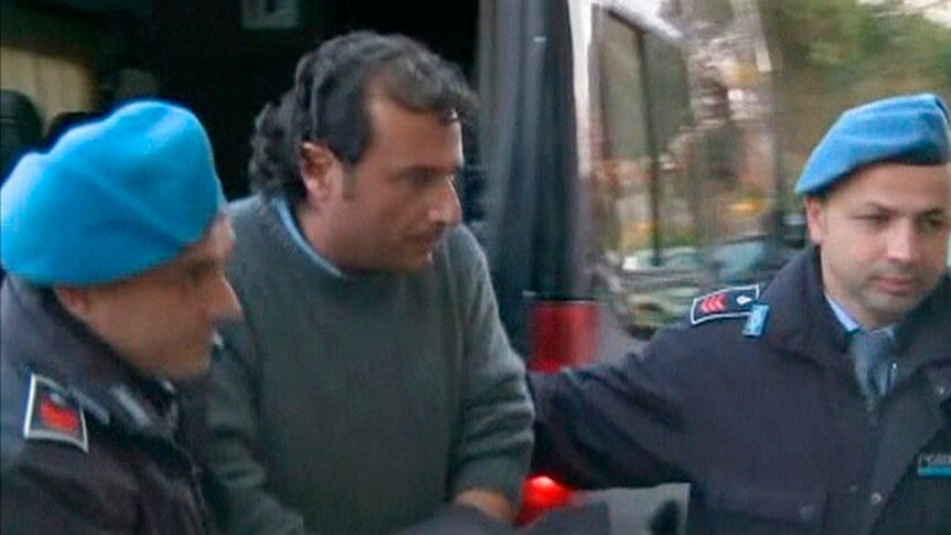 Captain Francesco Schettino is escorted into a prison by police officers at Grosseto.