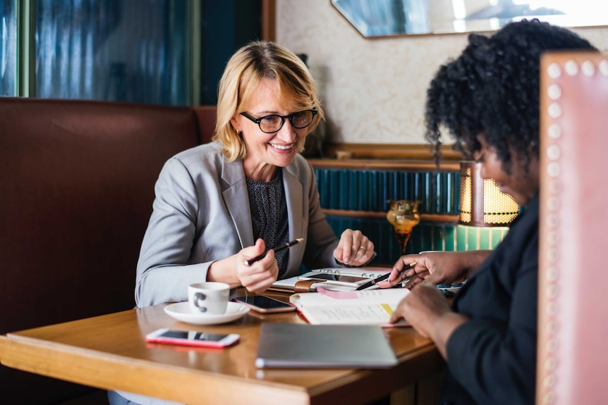 Two women sitting at a table smiling looking like they are discussing legal issues