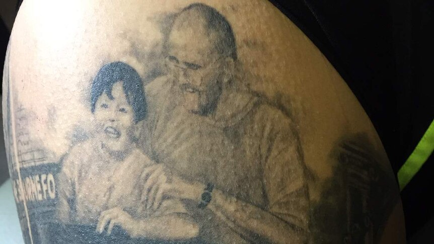 Close up of Mo's tattoo that shows her father with her sister Lavina as a young girl and a broken heart.