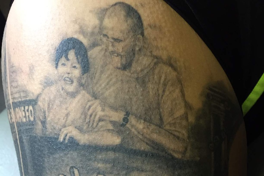 Close up of Mo's tattoo that shows her father with her sister Lavina as a young girl and a broken heart.