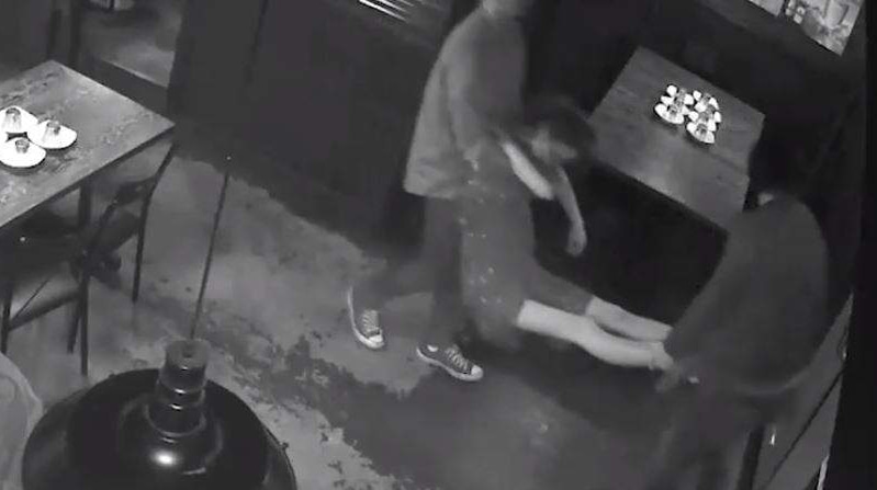 CCTV vision of an unconscious woman being carried out of a restaurant by her arms and legs.