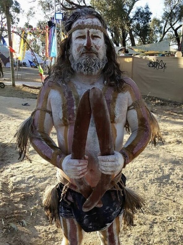An indigenous man in body paint at a music festival