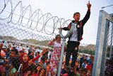 Refugee youth gestures from behind a barbed wire fence Nizip refugee camp near Gaziantep, Turkey, April 23, 2016