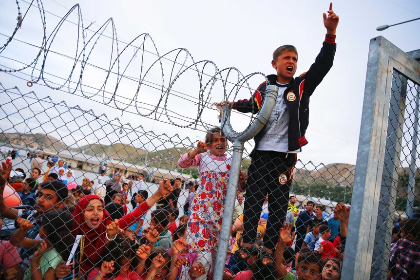 Refugee youth gestures from behind a barbed wire fence Nizip refugee camp near Gaziantep, Turkey, April 23, 2016