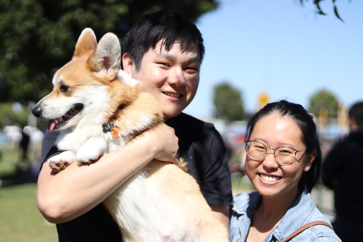 A man holding a corgi and a woman beside him, both smiling 