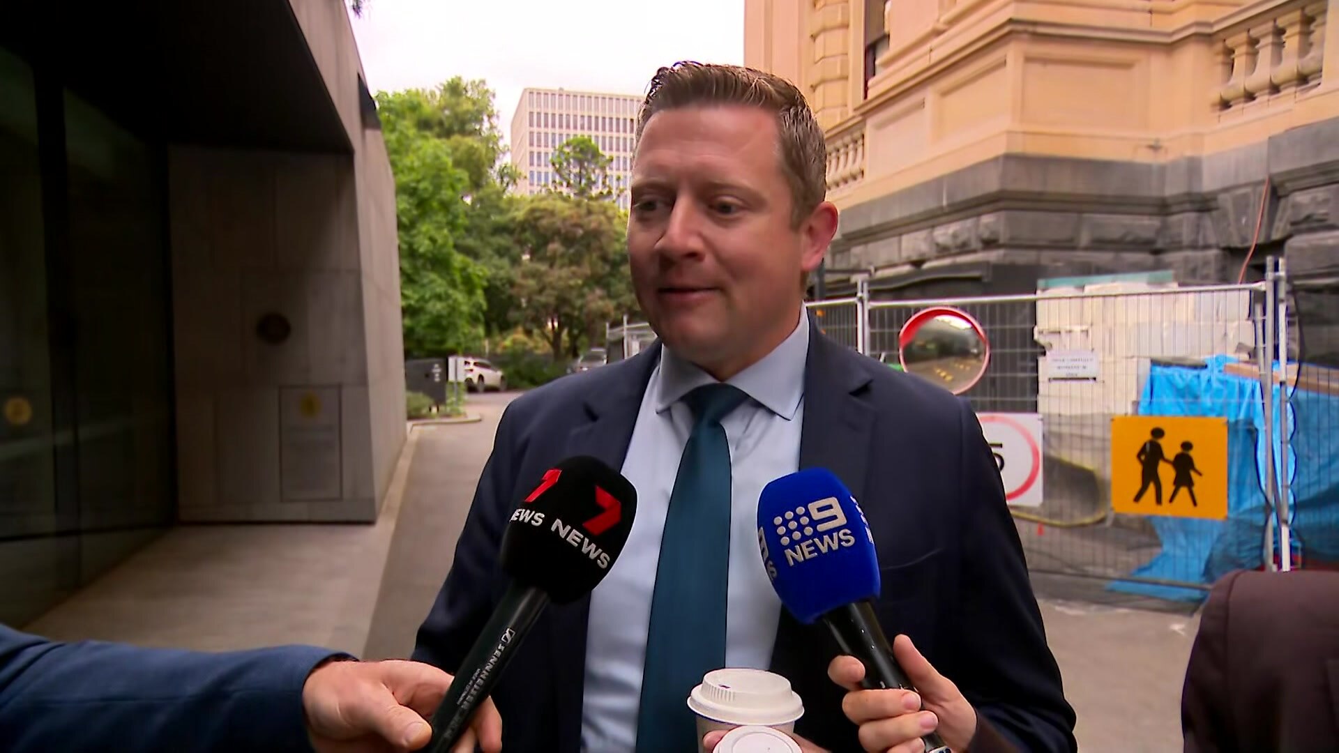 Brad Rowswell speaks to reporters, dressed in a suit outdoors.