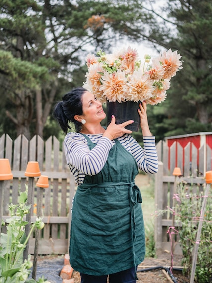 a lady wearing an apron holds a big bouquet of flowers.