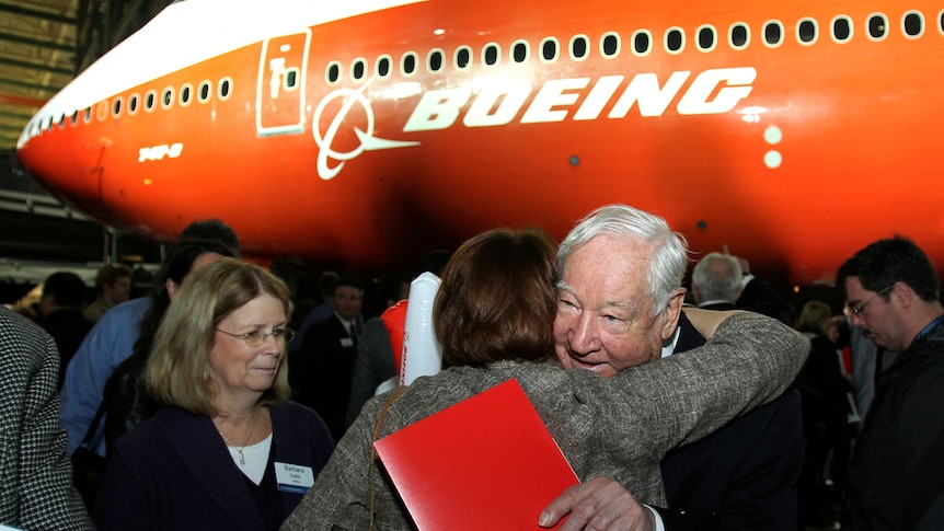 Mr Sutter hugs another person in front of a red and white Boeing. 