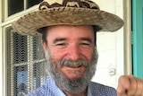 Bearded man smiles and wear a straw hat
