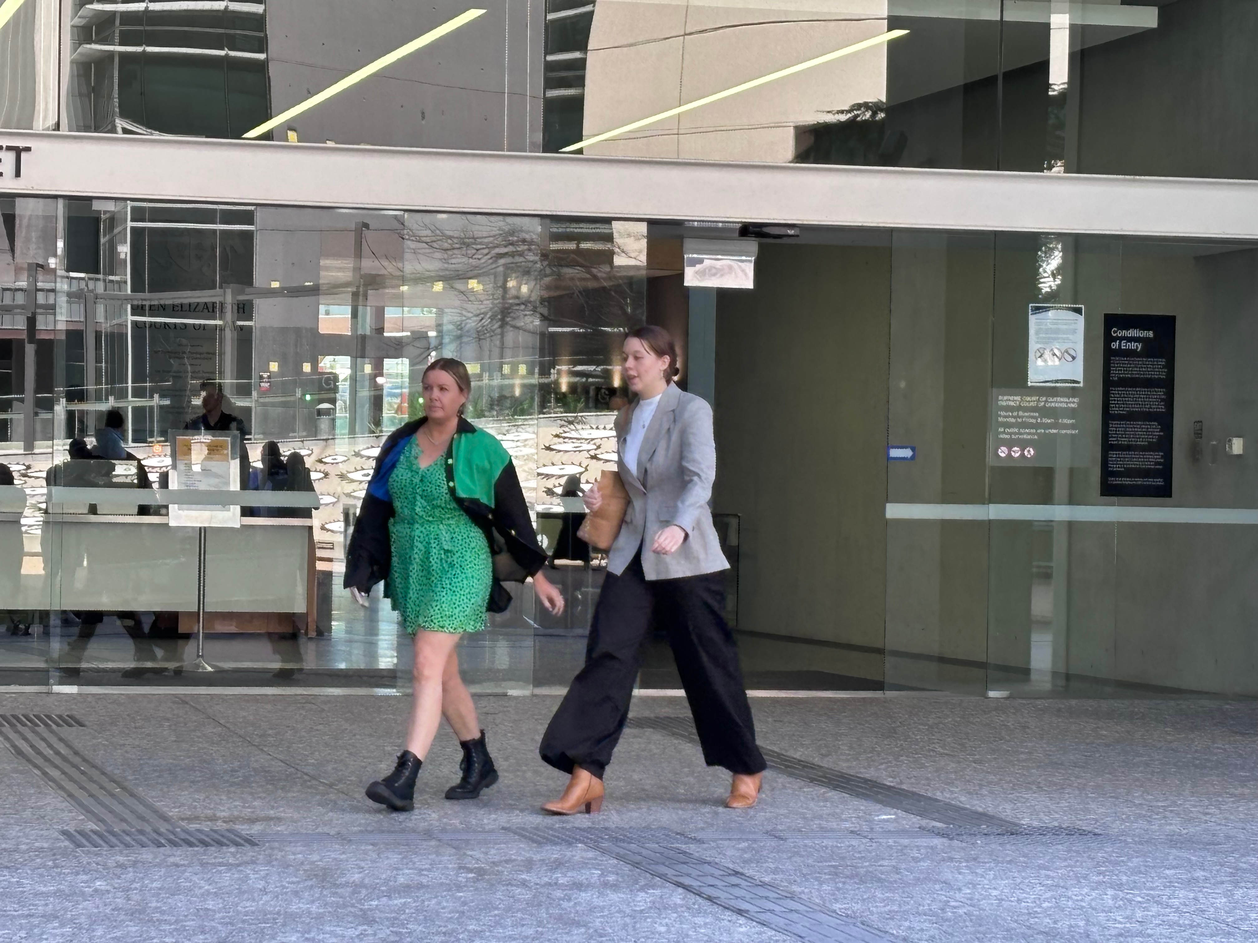 two women walk out of brisbane court building