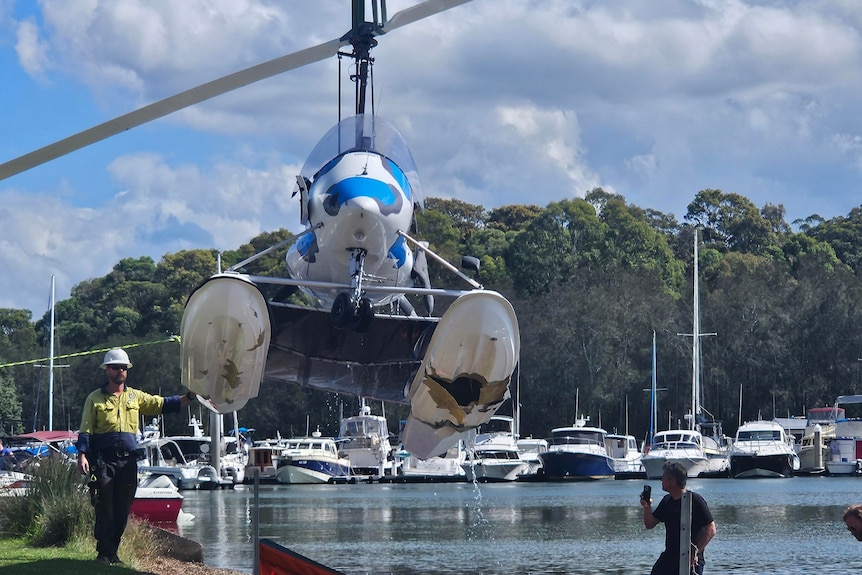 an aircraft is winched from water near a marina