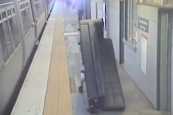 A large couch on the platform beside a departing train.