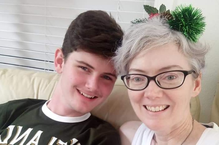 A woman and teenage boy on the couch wearing Christmas decorations