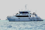 A police search boat floating on a silvery sea.
