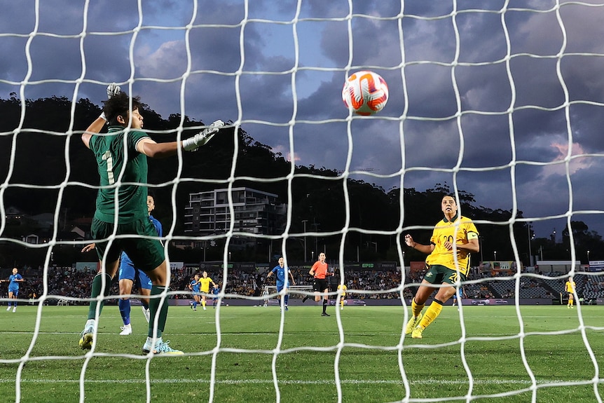 Seen from through the netting of the goal, the Matildas' Sam Kerr watches her shot at goal go past against Thailand's keeper.
