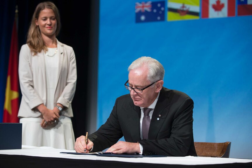 Andrew Robb signing a document.