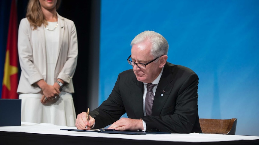 Andrew Robb signing a document.