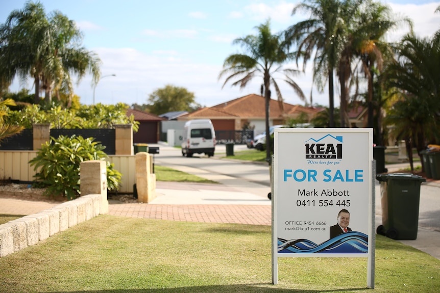 A for sale sign outside a suburban home