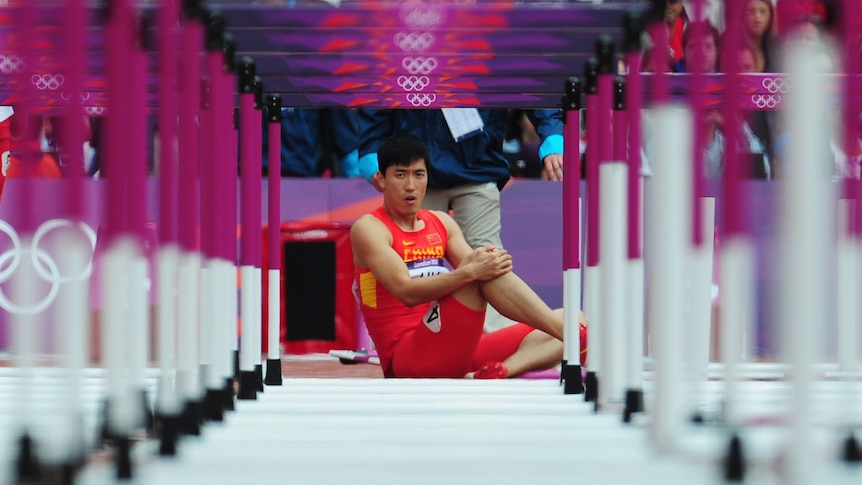 Chinese hurdler Liu Xiang sits on track after falling at first hurdle