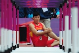 Chinese hurdler Liu Xiang sits on track after falling at first hurdle