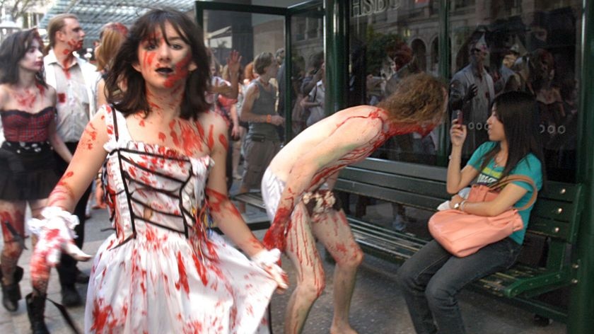 A woman sitting in a bus-stop photographs zombies