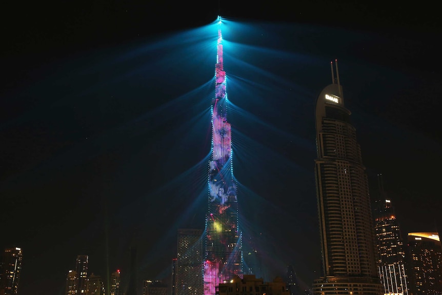 The Burj Khalifa tower building is lit up with a pink and blue LED light display.