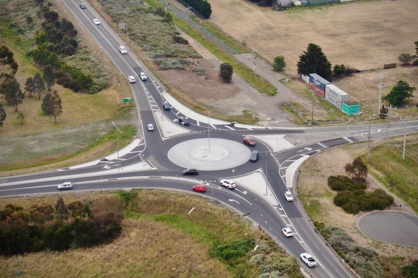 A drone image of traffic moving through a roundabout on a cloudy day.
