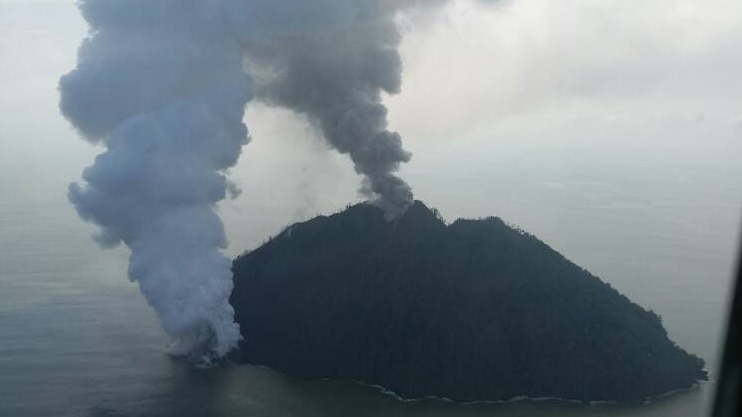 An aerial photograph shows two distinct plumes of smoke billowing from Kadovar island.