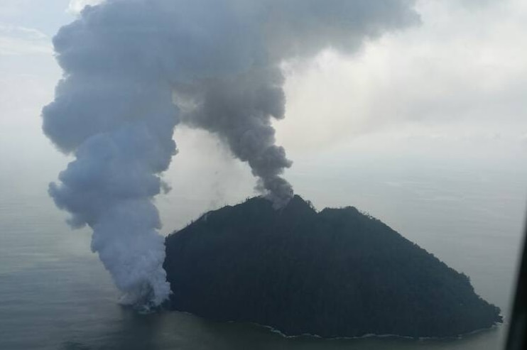 An aerial photograph shows two distinct plumes of smoke billowing from Kadovar island.